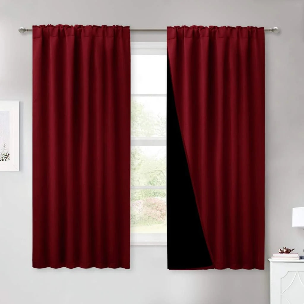 Burgundy blackout curtains with rod pocket hanging on a silver curtain rod by a window