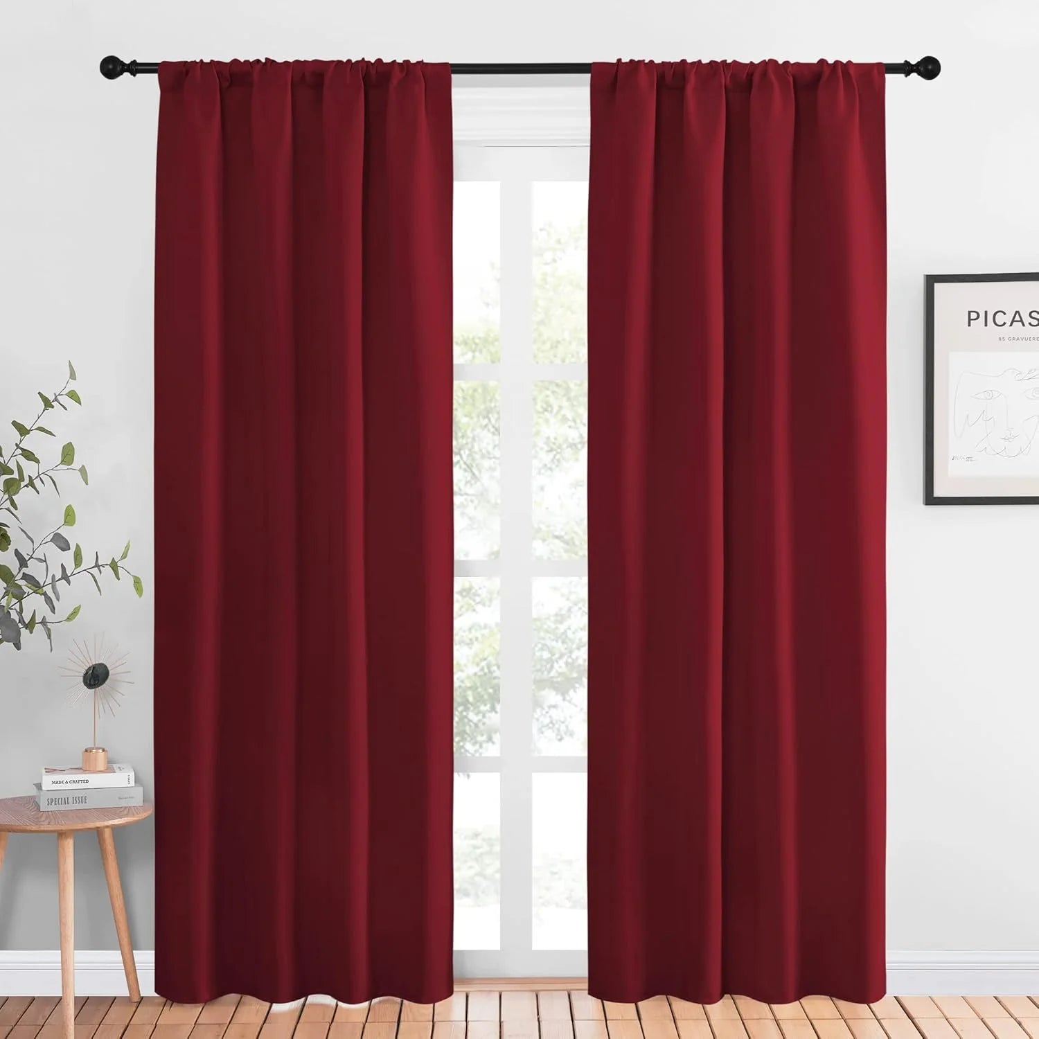 Burgundy blackout curtains hanging on a black rod in a bright modern room