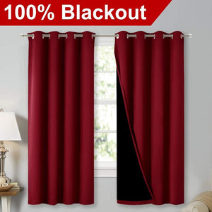 Burgundy grommet top blackout curtains hanging on a window rod, one panel revealing its black lining.