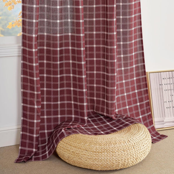 Burgundy and white plaid curtain panel hangs by a window, pooling on the floor next to a wicker pouf.