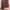 Rich burgundy window curtain with fine white plaid pattern, draped over a woven straw pouf.