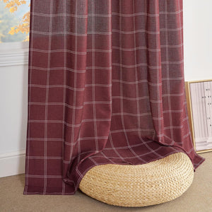 Rich burgundy window curtain with fine white plaid pattern, draped over a woven straw pouf.
