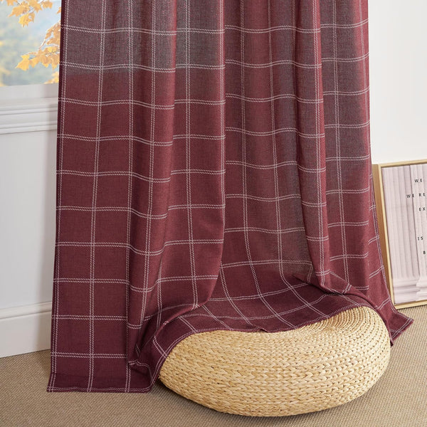 Rich burgundy window curtain with fine white plaid pattern, draped over a woven straw pouf.