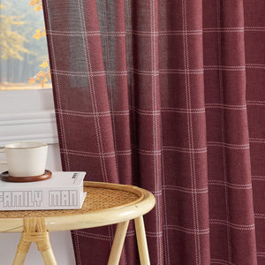 Rich burgundy curtain panel with a delicate white plaid pattern, draped beside a window, with a book and mug on a rattan table.