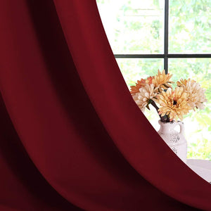 Burgundy solid curtain panel drapes, partially covering window with white vase and flowers.