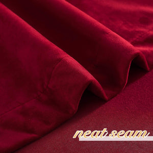 Rich burgundy velvet curtain fabric close-up, showcasing its soft texture and a neat seam.
