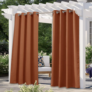 Pair of burnt orange outdoor privacy curtains with silver grommet tops hanging from a white pergola over a patio.