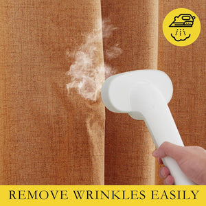 A hand holds a white steamer, removing wrinkles from a burnt orange, textured linen curtain.