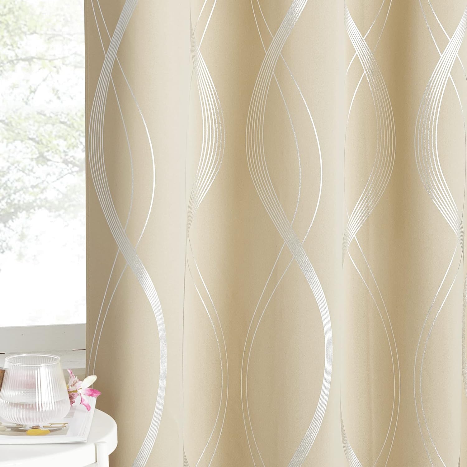 Elegant champagne curtain with shimmering silver abstract wave pattern hanging beside a window.