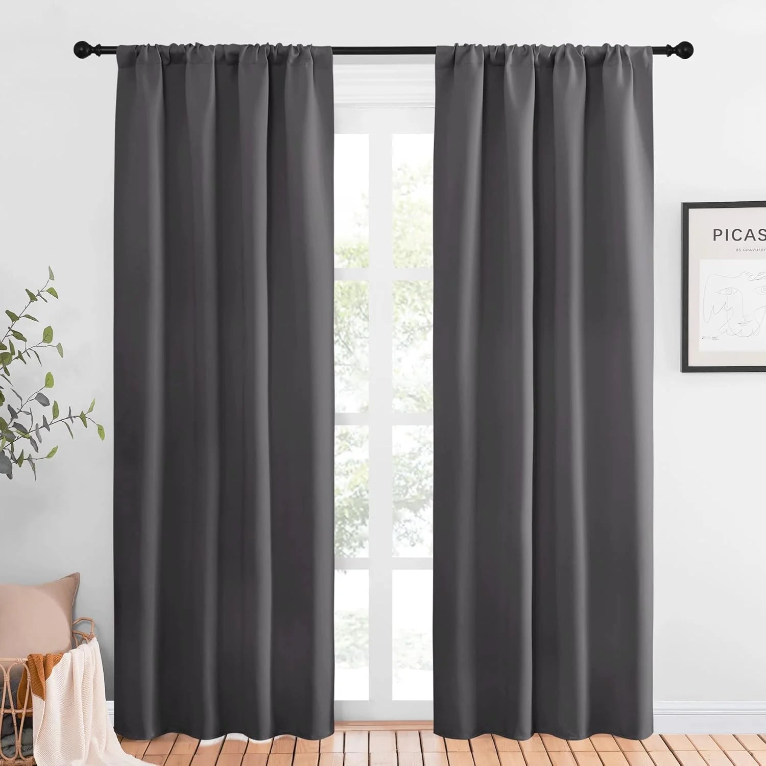 Charcoal gray blackout curtains with rod pocket top hanging on a black curtain rod