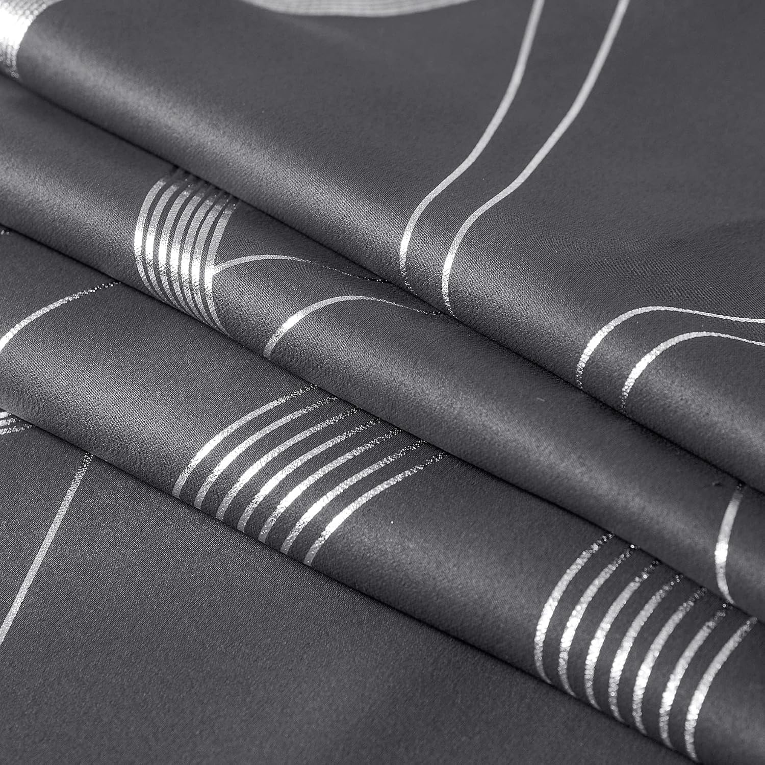 Textured charcoal gray fabric with reflective silver geometric pattern, solid and striped lines on folds.