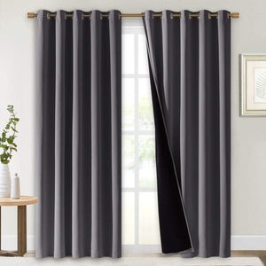 Pair of charcoal gray blackout curtains with metal grommet tops, one panel showing thick black thermal lining.