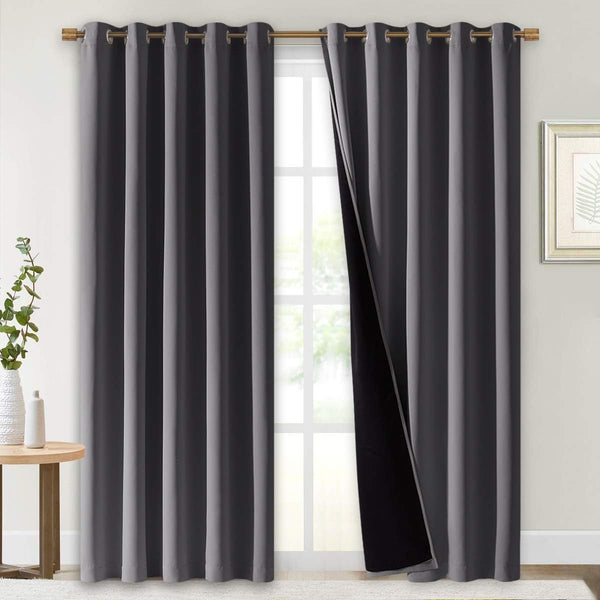 Pair of charcoal gray blackout curtains with metal grommet tops, one panel showing thick black thermal lining.