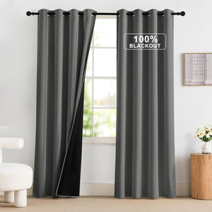 Pair of charcoal gray grommet blackout curtains with 100% light blocking lining, hanging on a black rod.