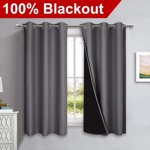Charcoal gray blackout curtains with silver grommet tops on a window, one revealing its dark lining.