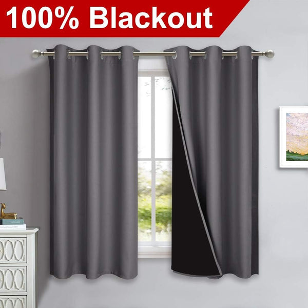 Charcoal gray blackout curtains with silver grommet tops on a window, one revealing its dark lining.
