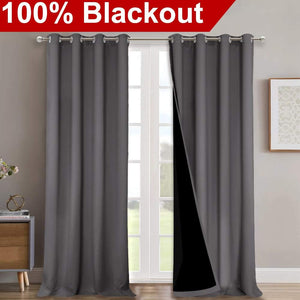 Two charcoal gray blackout curtain panels with silver grommets on a rod, one revealing black backing.