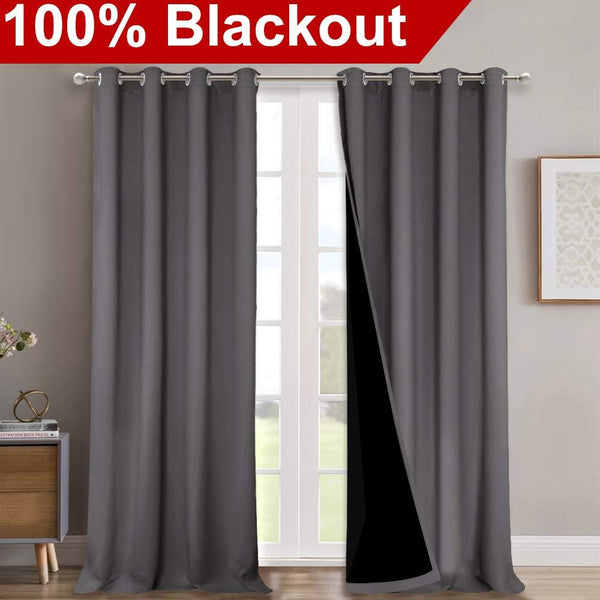 Two charcoal gray blackout curtain panels with silver grommets on a rod, one revealing black backing.