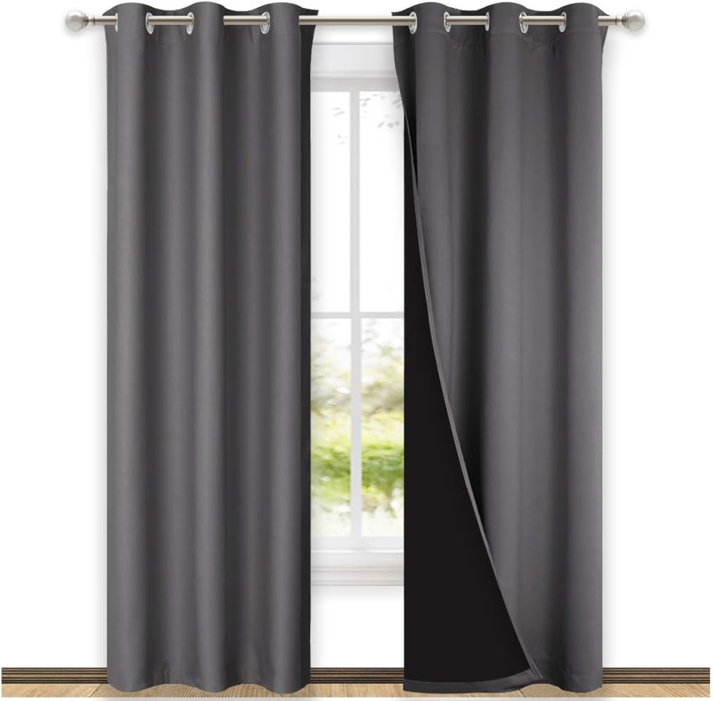 Charcoal gray grommet top blackout curtains on a silver rod. Black thermal lining visible on one panel.