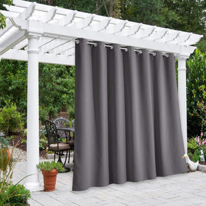 Charcoal gray outdoor privacy curtain with silver grommets hangs from a white pergola on a patio.