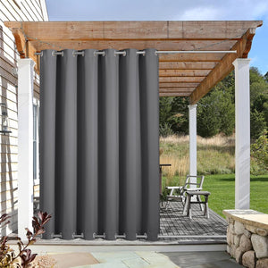 Thick charcoal gray outdoor curtain with top and bottom silver grommets hangs on a patio pergola, offering privacy.