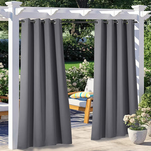 Charcoal gray outdoor curtains with grommet tops, hanging from a white pergola on a sunny patio.
