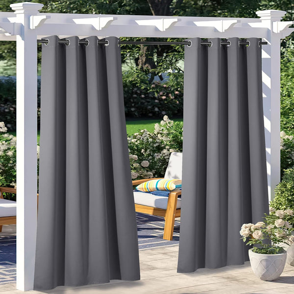 Charcoal gray outdoor curtains with grommet tops, hanging from a white pergola on a sunny patio.