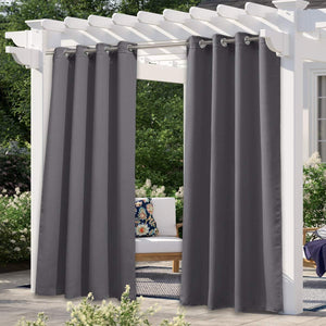 Charcoal gray outdoor curtains with grommet tops hanging from a white pergola, providing shade on a patio.