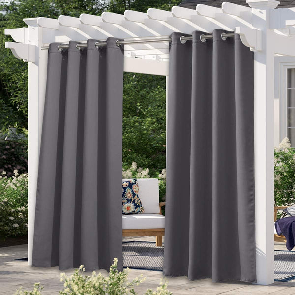 Charcoal gray outdoor curtains with grommet tops hanging from a white pergola, providing shade on a patio.
