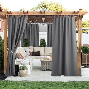 Charcoal gray tab top outdoor curtains hang on a wooden pergola, creating privacy for a patio living area.