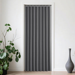Smooth charcoal gray pleated curtain on black rod covering a white doorway in a minimalist room.