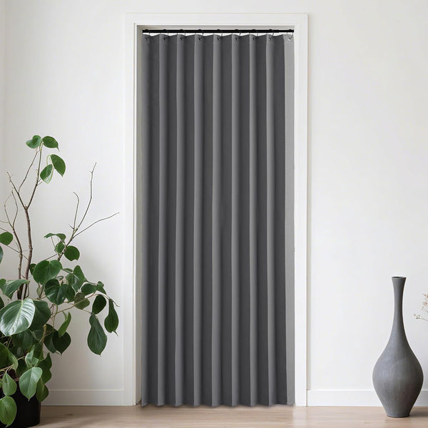 Smooth charcoal gray pleated curtain on black rod covering a white doorway in a minimalist room.