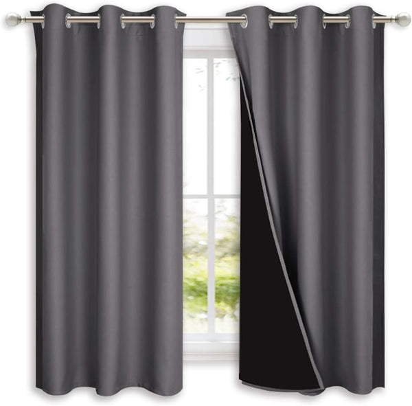 Charcoal grey grommet top blackout curtains, one revealing dark lining, on a silver rod.