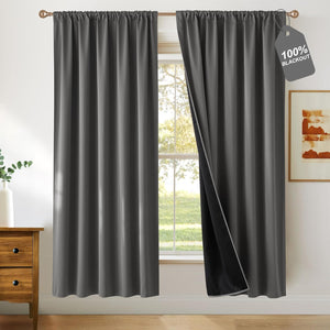 Charcoal grey blackout curtains with gathered top, one panel open showing dark insulating lining.