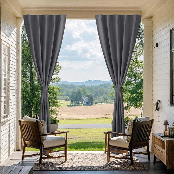 Charcoal grey outdoor patio curtains with tie-backs on a white porch, framing a scenic rural view.