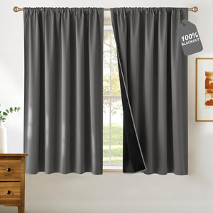 Charcoal grey rod pocket blackout curtains with gathered top hung on bronze rod, showing dark lining.