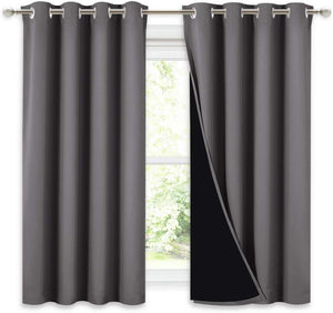Charcoal grey blackout curtains with silver grommet top. Black liner visible, hanging over a window.
