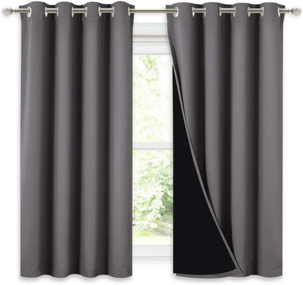 Charcoal grey blackout curtains with silver grommet top. Black liner visible, hanging over a window.