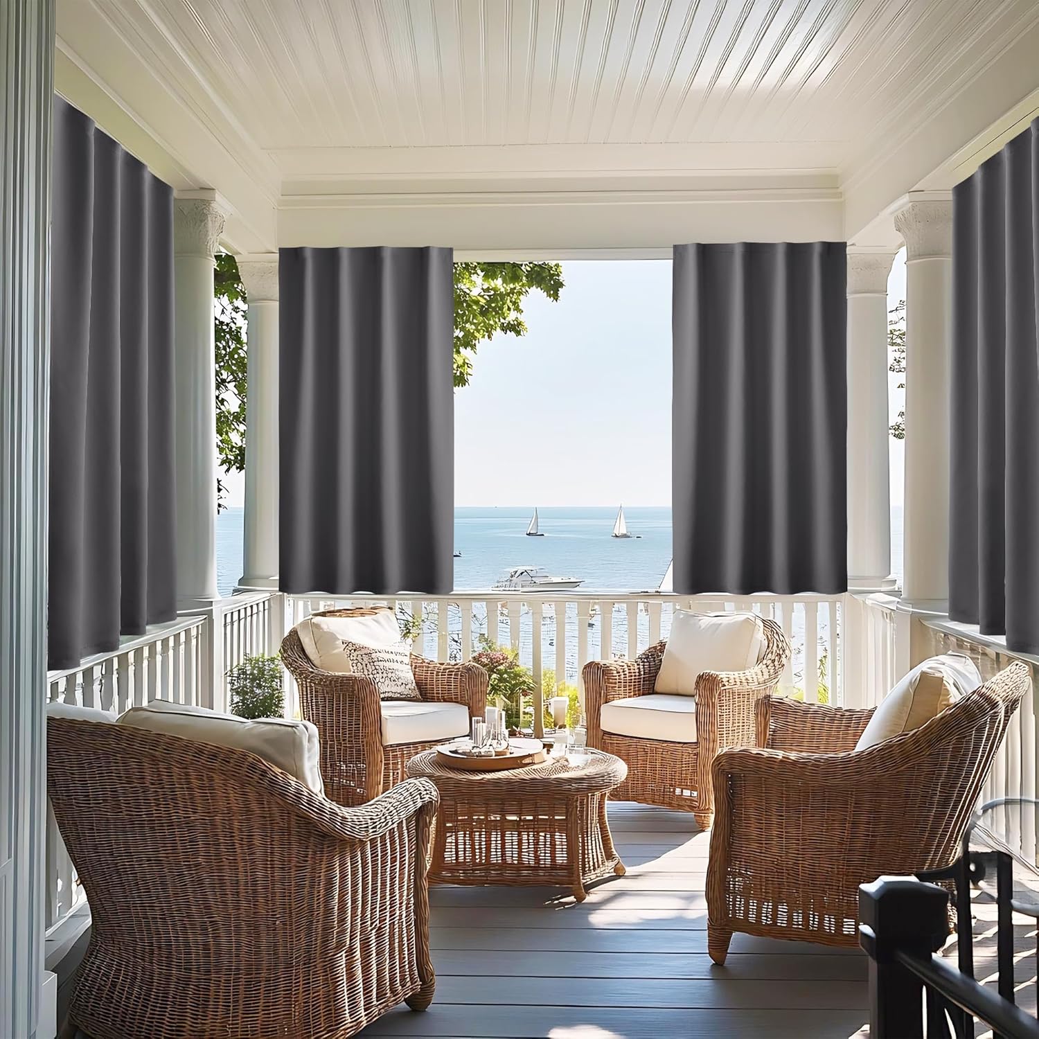 Charcoal grey outdoor curtains hang on a white porch, providing shade for wicker furniture.
