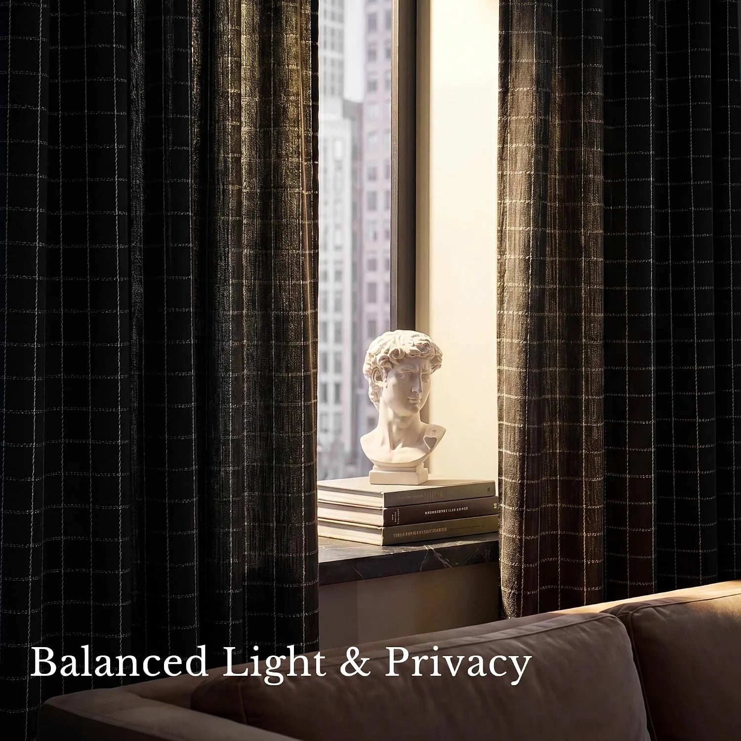 Charcoal grid pattern curtains partially closed in a modern living room with a classical bust on the windowsill overlooking a city view.