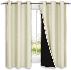 Pair of cream grommet blackout curtains with a visible dark lining, hung on a silver rod.