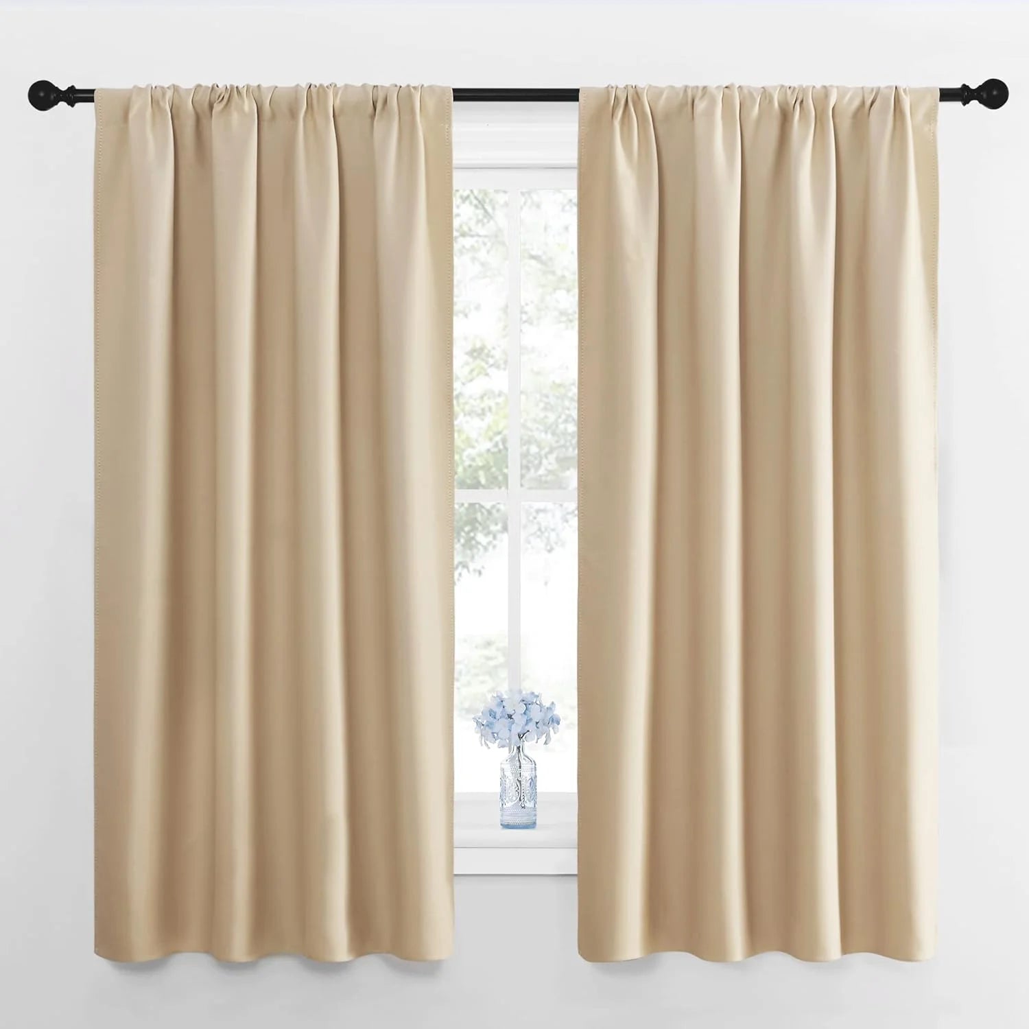 Cream blackout curtains with rod pocket top hanging on a black curtain rod