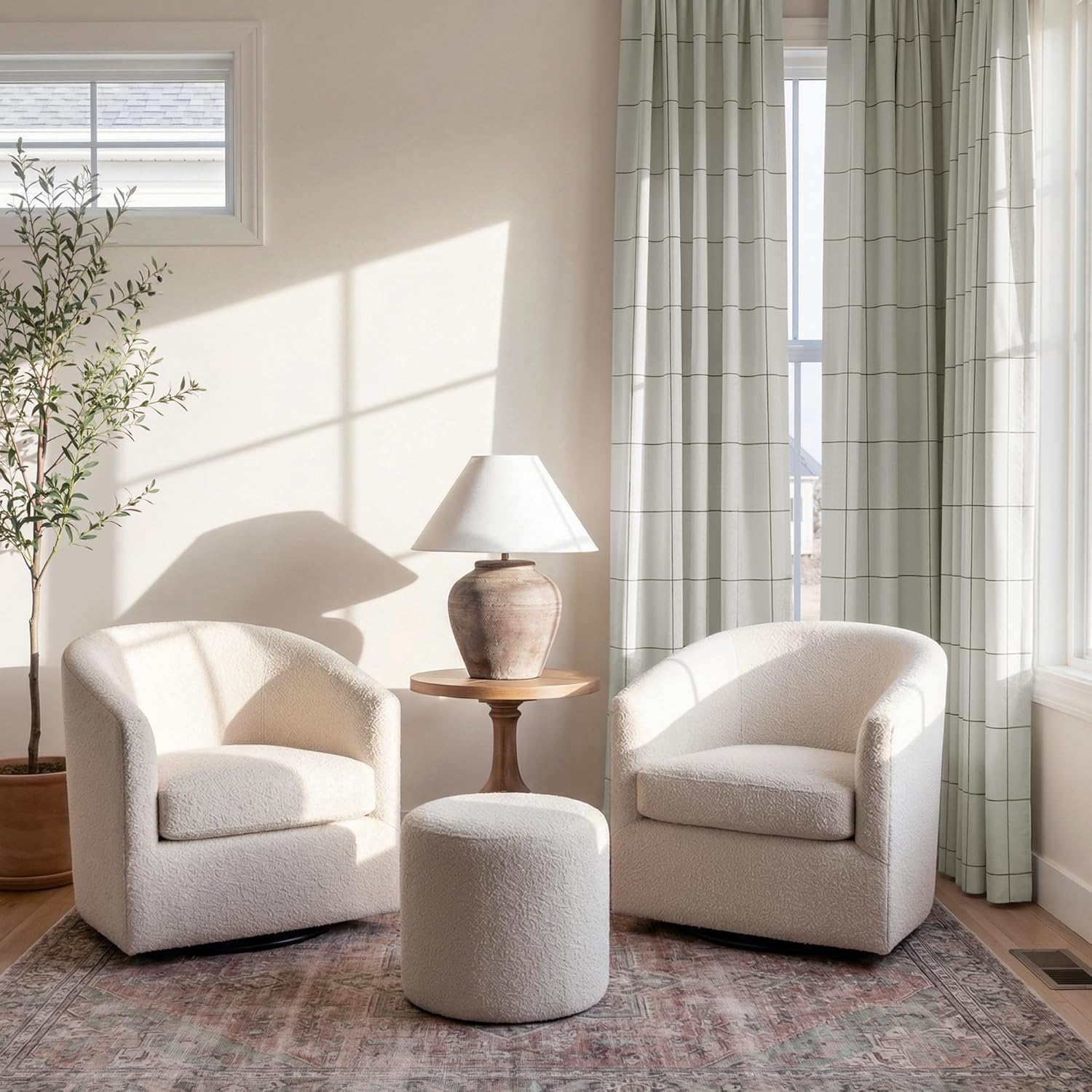 Pair of cream boucle swivel chairs and matching ottoman in a sunlit modern living room.