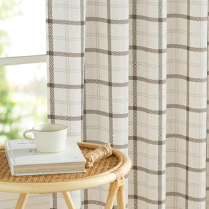 Cream and brown plaid window curtain made from textured fabric hanging by a window with natural light.