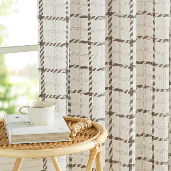 Cream and brown plaid window curtain made from textured fabric hanging by a window with natural light.