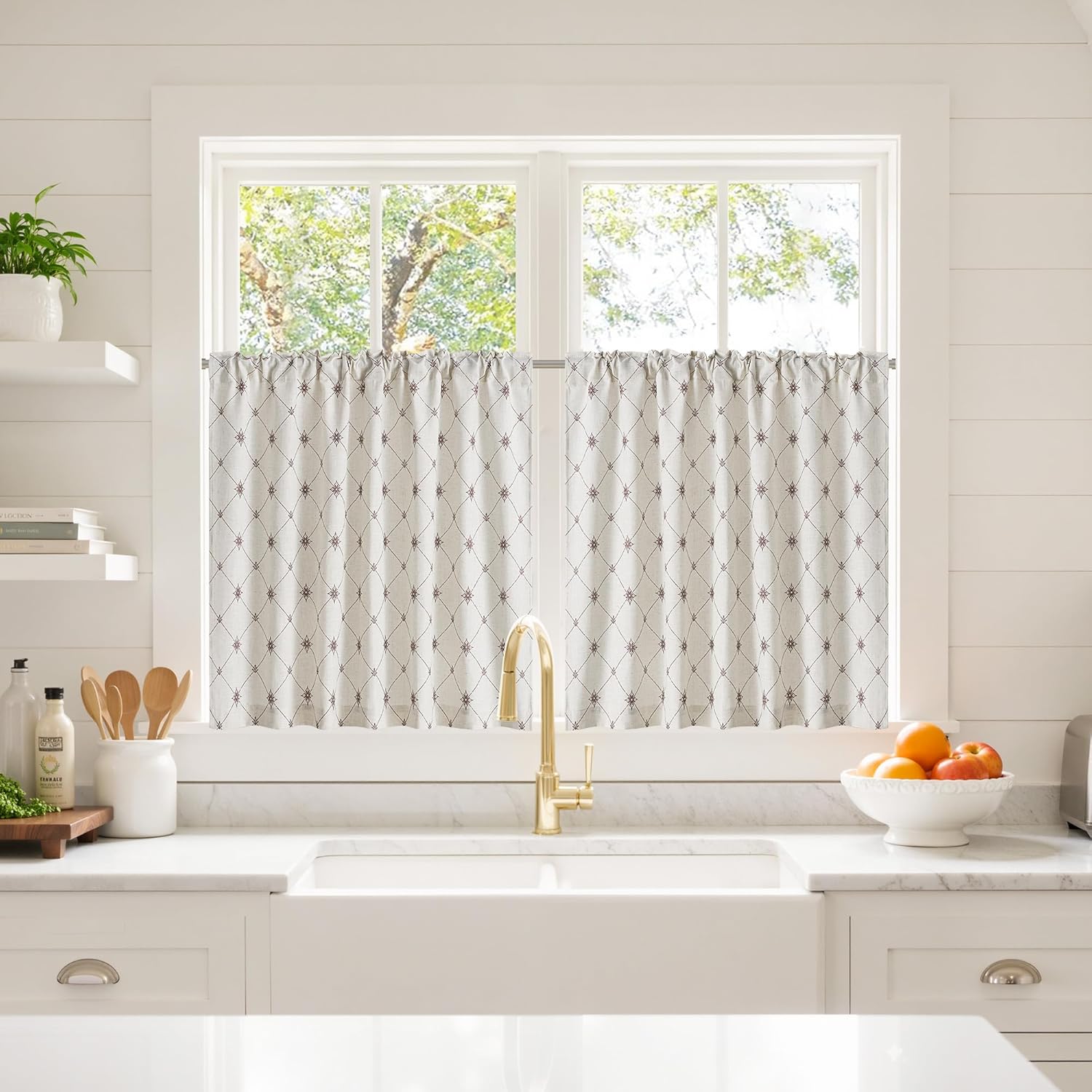 Light filtering cream cafe curtains with a diamond and star pattern over a farmhouse kitchen sink.