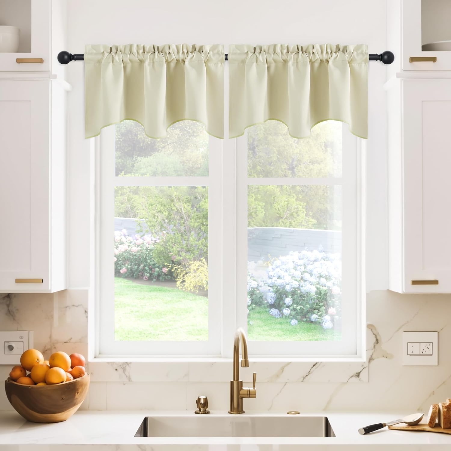 Cream gathered rod pocket valance with a scalloped bottom edge hangs over a kitchen window.