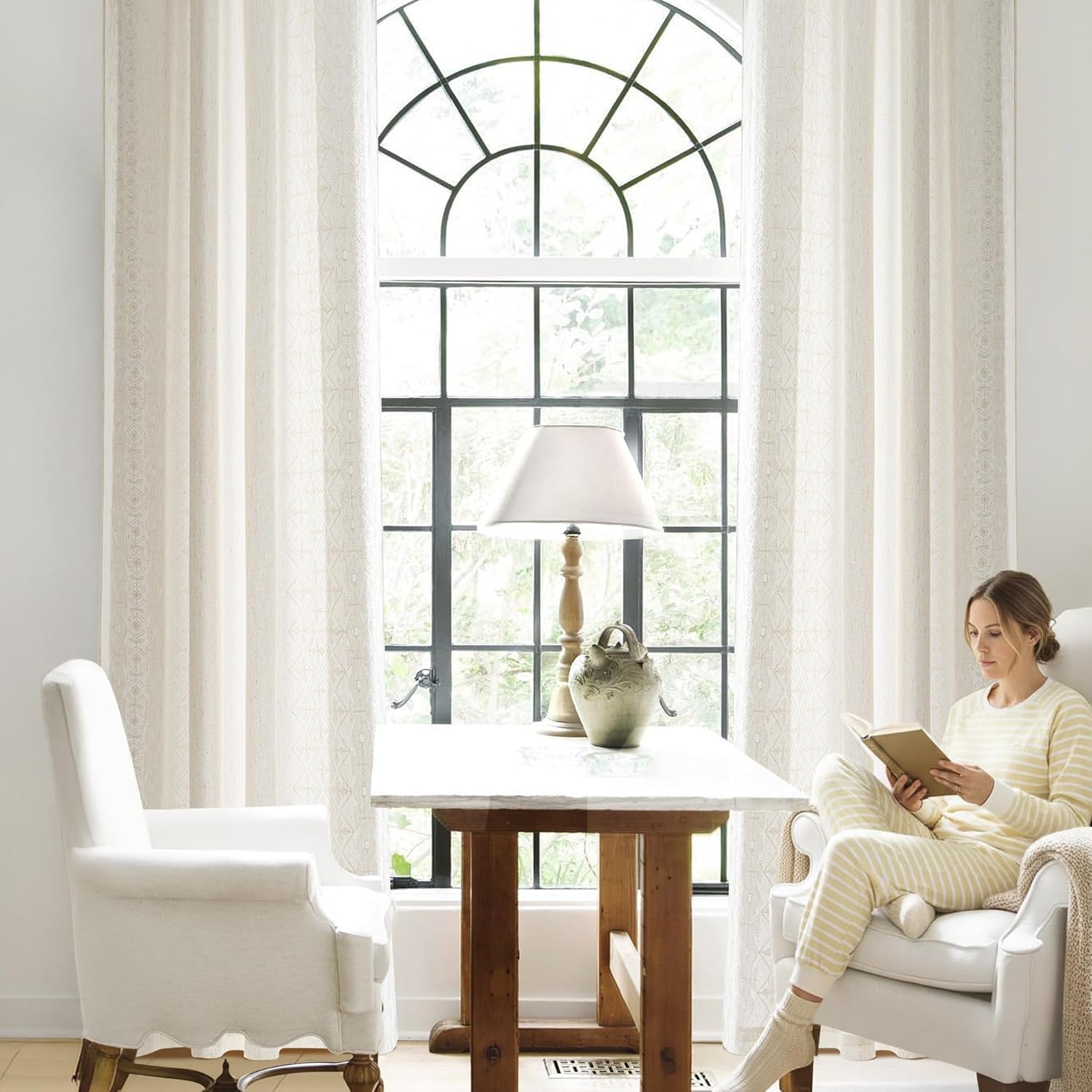 Cream woven curtains with a subtle geometric pattern framing an arched window.