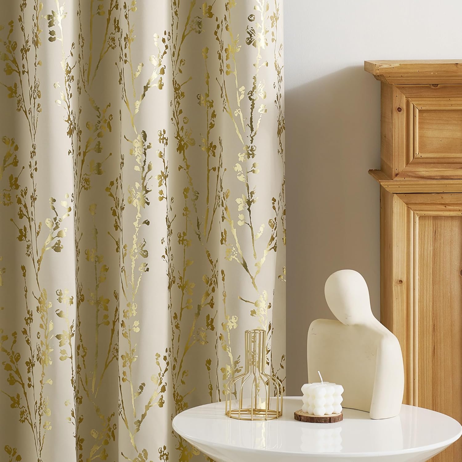Elegant cream curtains with shimmering gold floral branch pattern, hanging softly with visible folds.