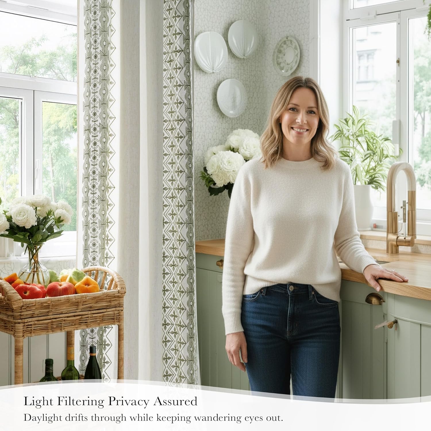 Cream light filtering curtains with green geometric border pattern in a sunny kitchen window.